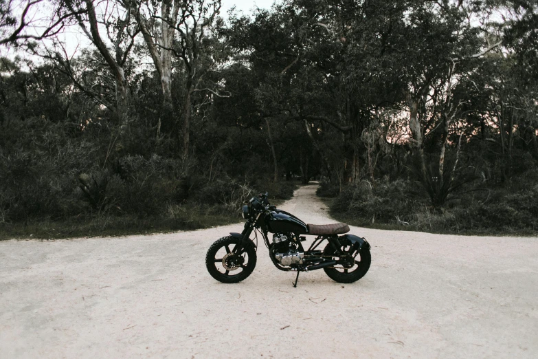 a motorcycle parked on the side of a dirt road, a picture, by Lee Loughridge, unsplash contest winner, sydney park, sitting in the forrest, prototype, coastal