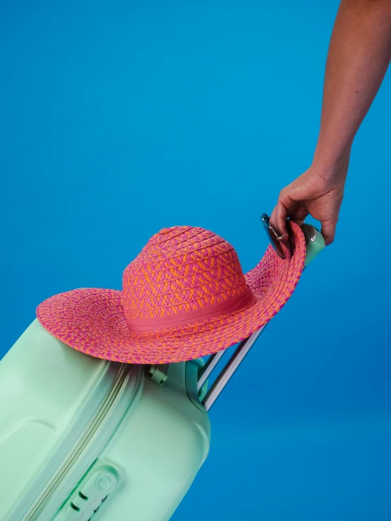 a person pulling a piece of luggage with a hat on top of it, a colorized photo, by Rachel Reckitt, pexels contest winner, dayglo pink, close up half body shot, summer color pattern, mauve and cinnabar and cyan