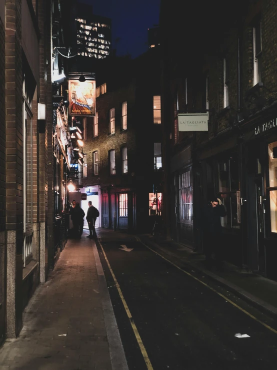 a person walking down a city street at night, london at night, shady alleys, background image, multiple stories