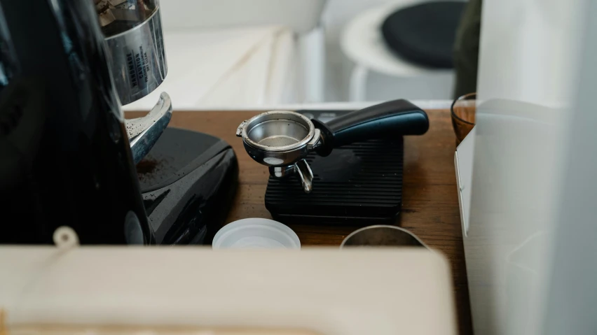 a coffee maker sitting on top of a wooden table, various items, detailed product image, spoon placed, at checkout