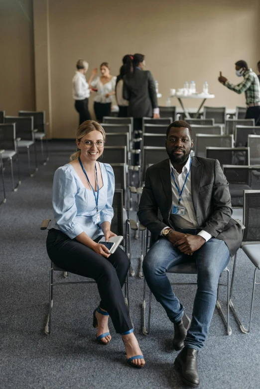 a couple of people sitting in chairs in a room, ready for a meeting, standing in an arena, varying ethnicities, aleksandra waliszewska