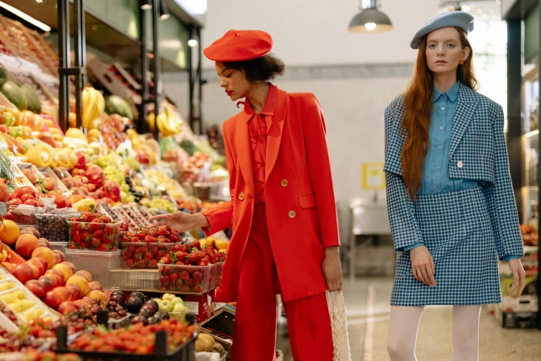 a couple of women standing next to each other in front of a fruit stand, trending on pexels, magic realism, red suit, sadie sink, inside a supermarket, fashion week