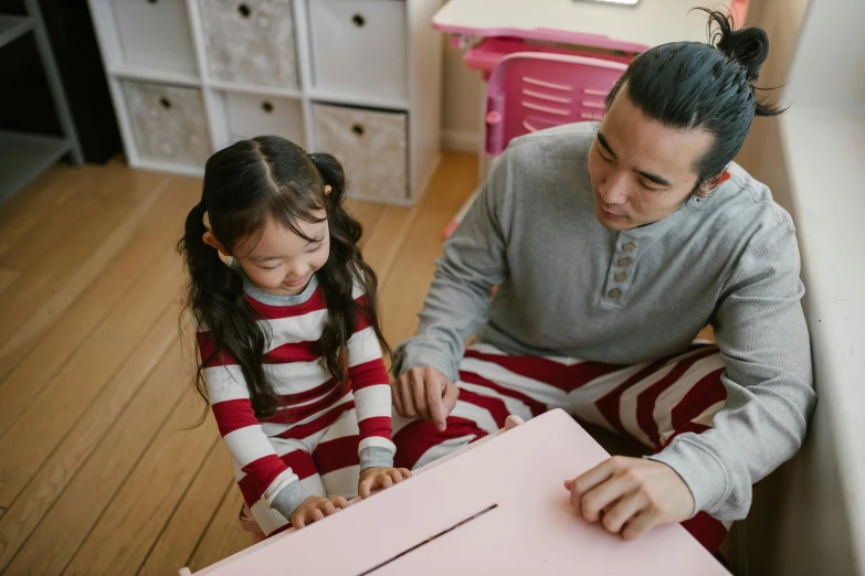 a man and a little girl sitting on the floor, pexels contest winner, interactive art, board games on a table, wearing pajamas, red and white stripes, asian descent