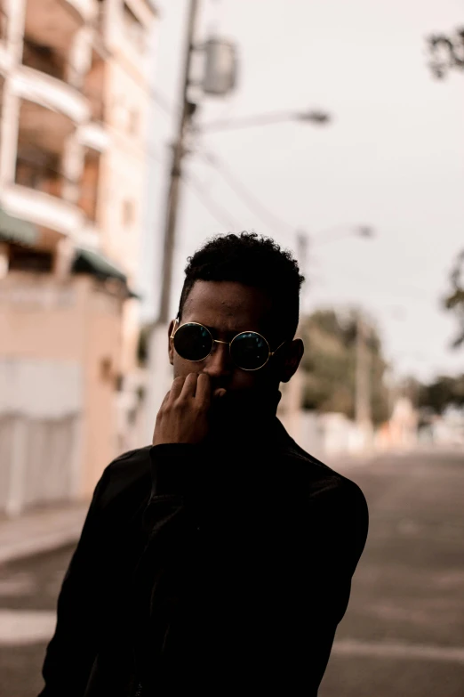 a man standing on a street talking on a cell phone, an album cover, by Alexis Grimou, pexels contest winner, wearing shades, sharp black skin, profile image, casual pose