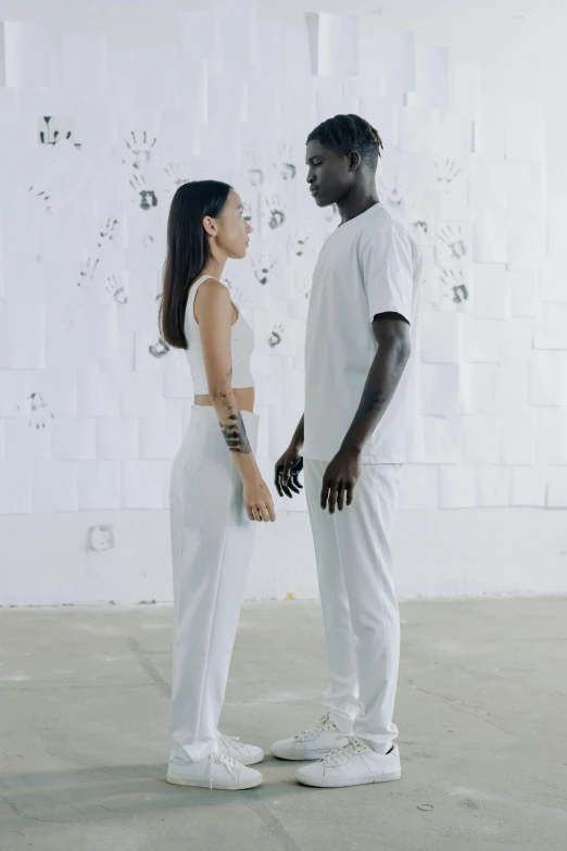 a man and a woman standing next to each other, inspired by Fei Danxu, afrofuturism, in white room, connection rituals, white pants, facing each other