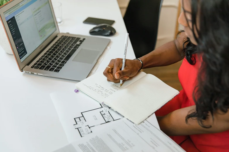 a woman sitting at a desk in front of a laptop, by Carey Morris, pexels contest winner, architecture blueprint copy, pen and paper, alexis franklin, walking down