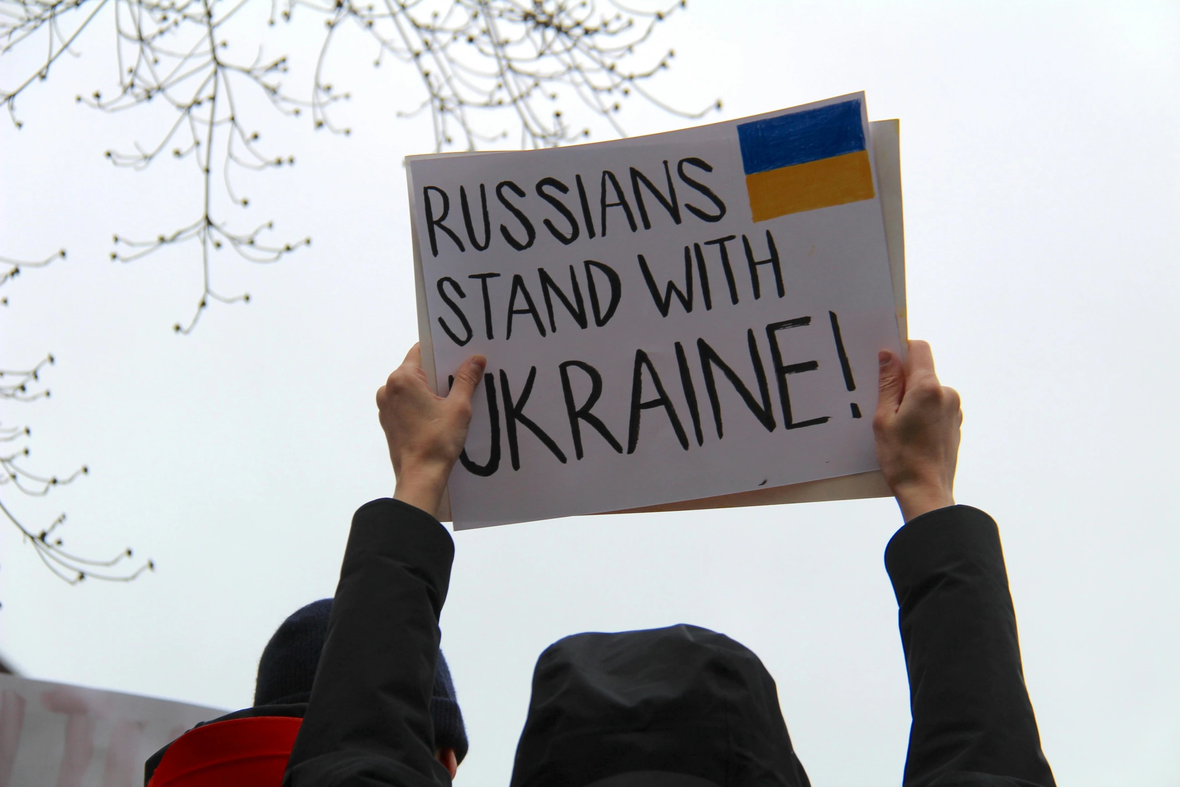 a person holding a sign that says russians stand with ukraine, a photo, by Julia Pishtar, shutterstock, square, 🇺🇦, rioting, on a canva