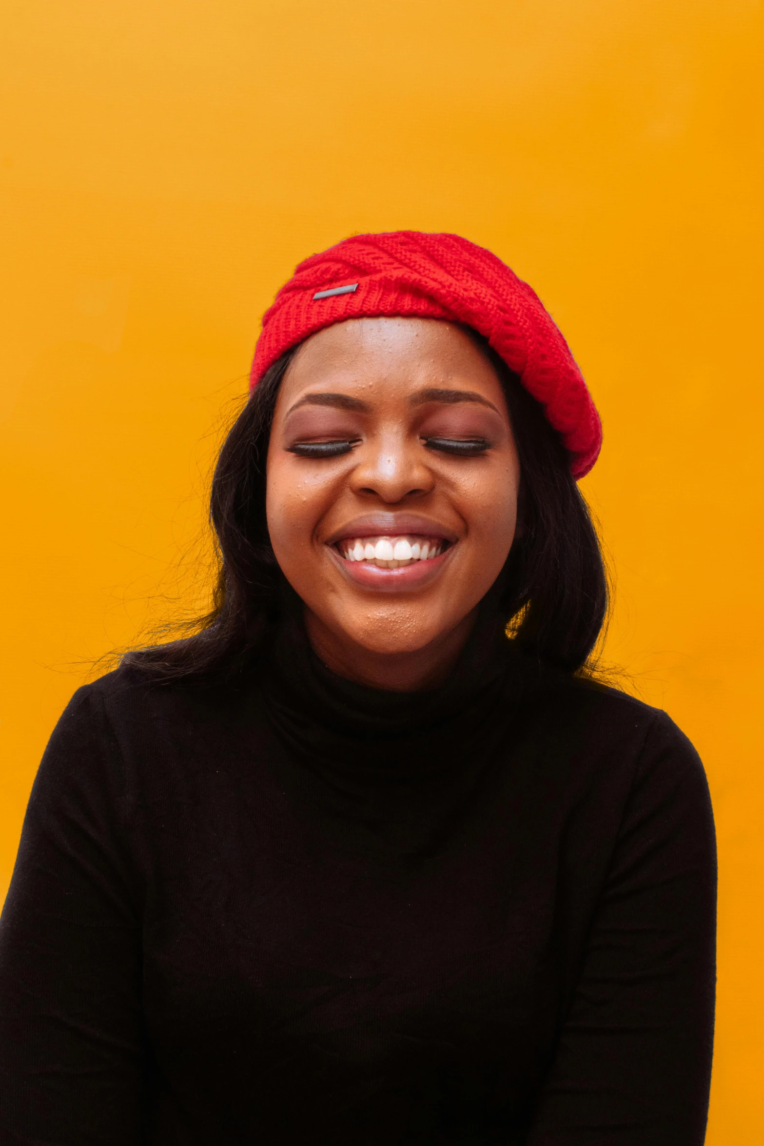 a woman in a black shirt and a red hat, trending on pexels, yellow backdrop, wearing a beret, smiling sweetly, dark skinned