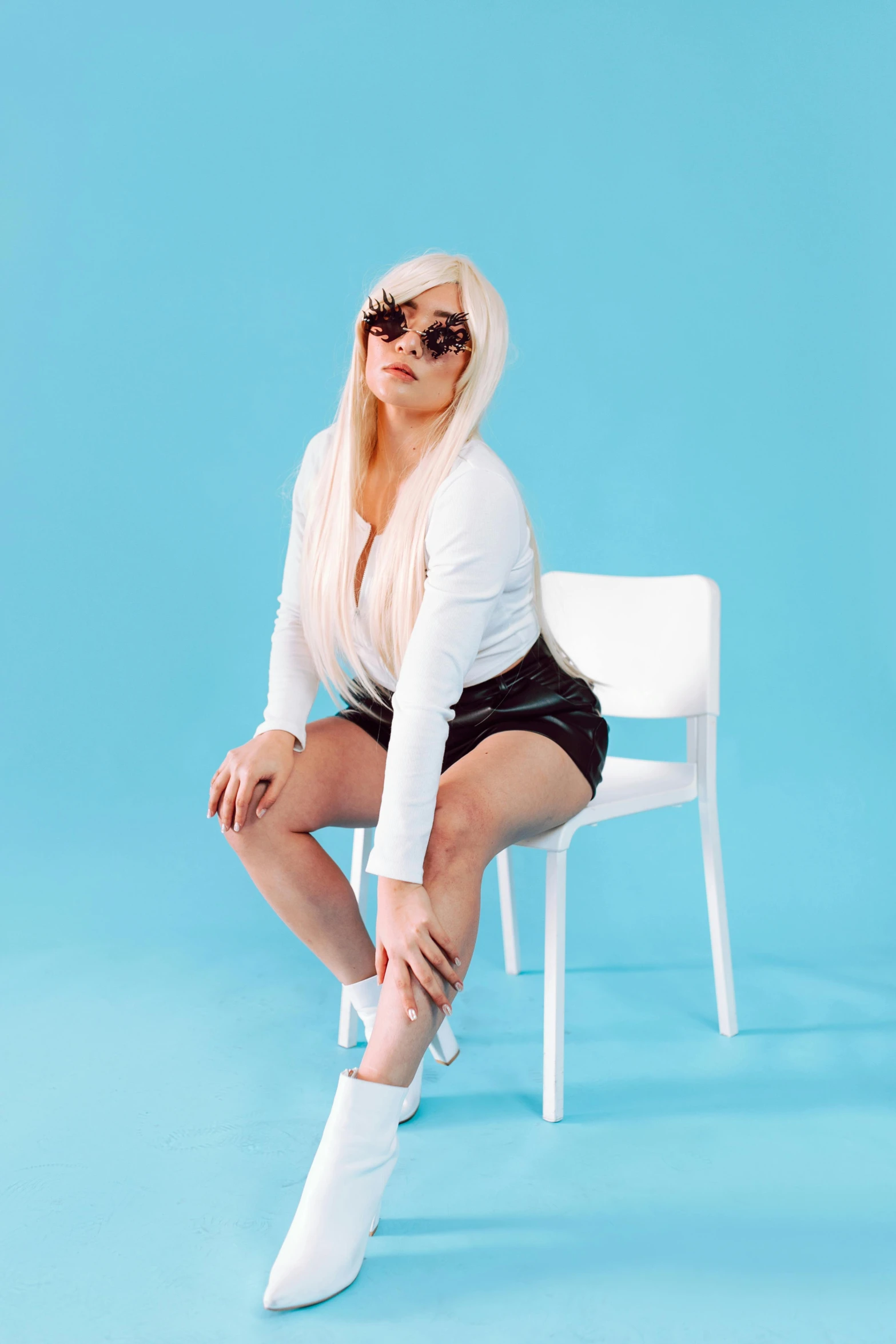 a woman sitting on top of a white chair, an album cover, inspired by Elsa Bleda, unsplash, nicki minaj curvy, wearing shades, white straight hair, thighs