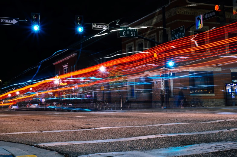 a blurry photo of a city street at night, by Carey Morris, unsplash contest winner, photorealism, light trail, kansas town at midnight, blue and orange lighting, sprawling