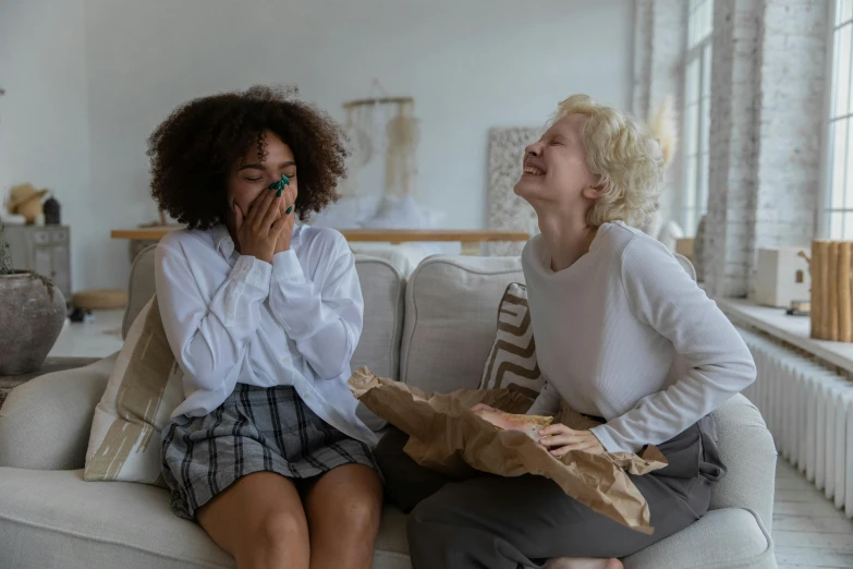 a couple of women sitting on top of a couch, pexels contest winner, earing a shirt laughing, woman crying, diverse, short curly blonde haired girl