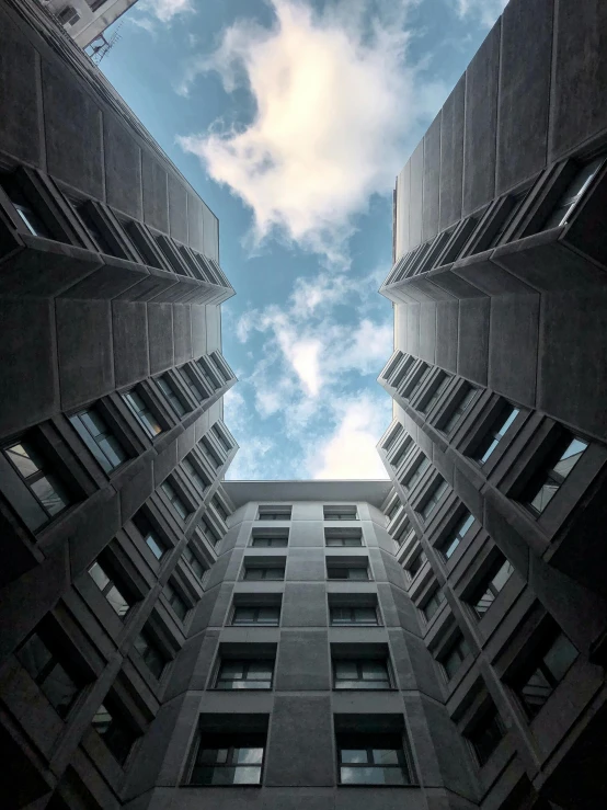 a couple of tall buildings sitting next to each other, inspired by André Kertész, pexels contest winner, brutalism, 3 layers of sky above each other, paul barson, view from ground, high - angle