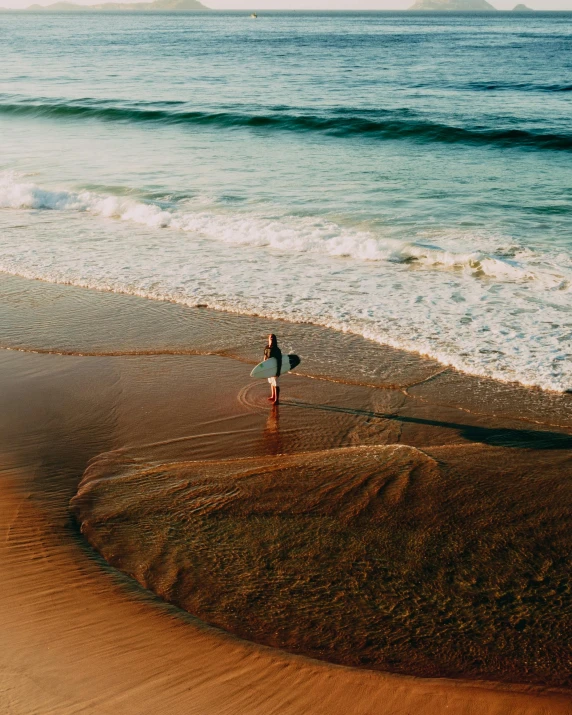 a person walking on a beach with a surfboard, by Elsa Bleda, unsplash contest winner, bird view, late afternoon, vsco, multiple stories