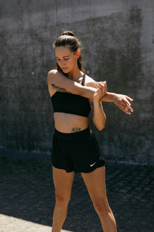 a woman holding a tennis racquet on a tennis court, inspired by Louisa Matthíasdóttir, wearing a black cropped tank top, arms stretched out, bra and shorts streetwear, profile image