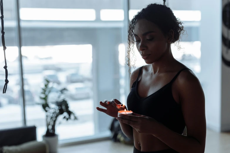 a woman standing in front of a window holding a cell phone, pexels contest winner, light and space, on a candle holder, athletic muscle tone, figure meditating close shot, avatar image