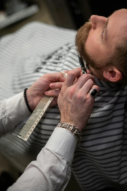 a man getting his hair cut by a barber, a stipple, happening, wearing steel collar, hands on face, red beard, press shot