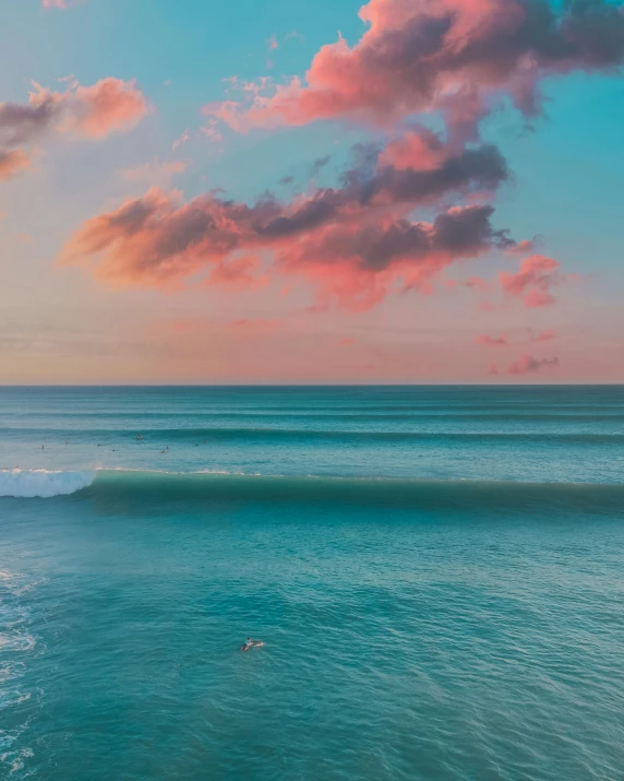 a person riding a surfboard on top of a wave, the sky is pink, the ocean