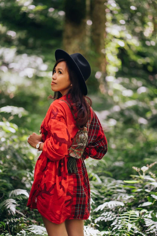 a woman standing in the middle of a forest, by Julia Pishtar, sumatraism, red kimono with flower patterns, tartan garment, wearing a travel hat, in style of ruan jia