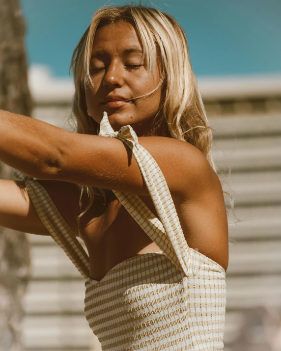 a woman taking a selfie with her cell phone, an album cover, by Grace Clements, trending on unsplash, happening, cute checkerboard sundress, slightly tanned, showing off biceps, gif