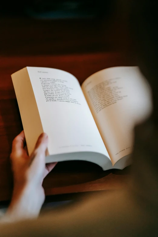 a person reading a book on a table, by James Bard, unsplash, hidden message, lit from bottom, half turned around, portrait shot