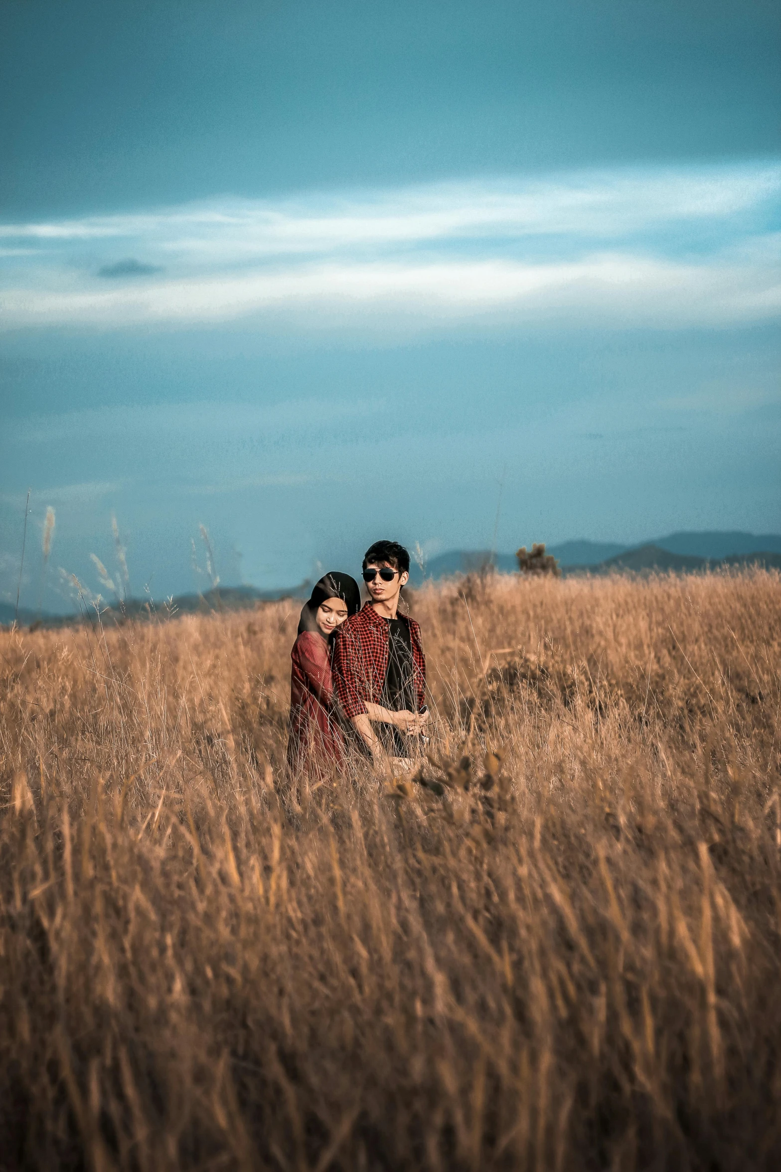 a man and a woman sitting in a field, a picture, pexels contest winner, indonesia, 256435456k film, standing in midground, medium format