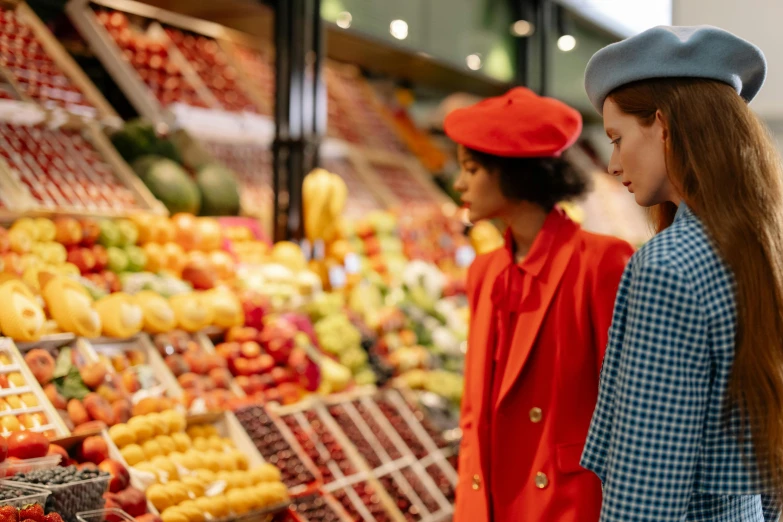 a couple of women standing next to each other in front of a fruit stand, by Julia Pishtar, pexels, red dress and hat, inside a supermarket, inspect in inventory image, wearing red jacket