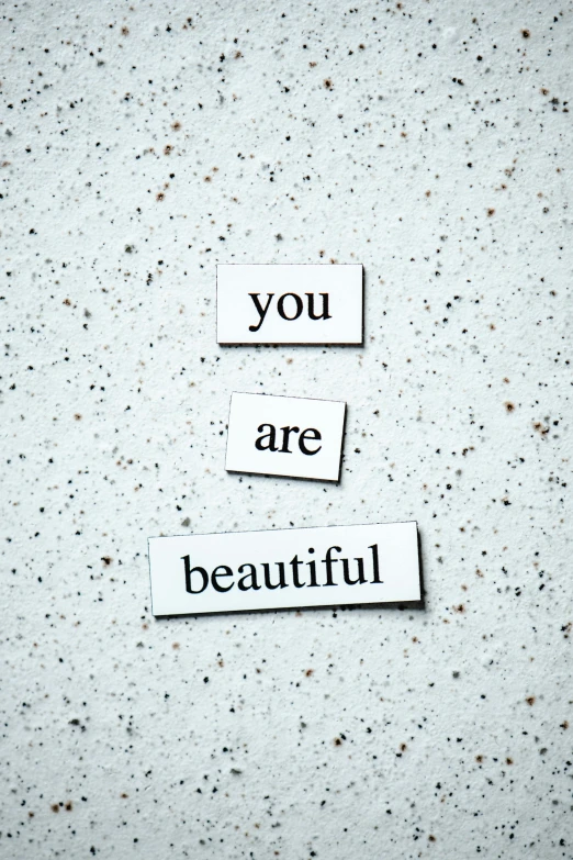 a piece of paper with the words you are beautiful written on it, by Bernie D’Andrea, unsplash, made of all white ceramic tiles, grey, half image, beauty