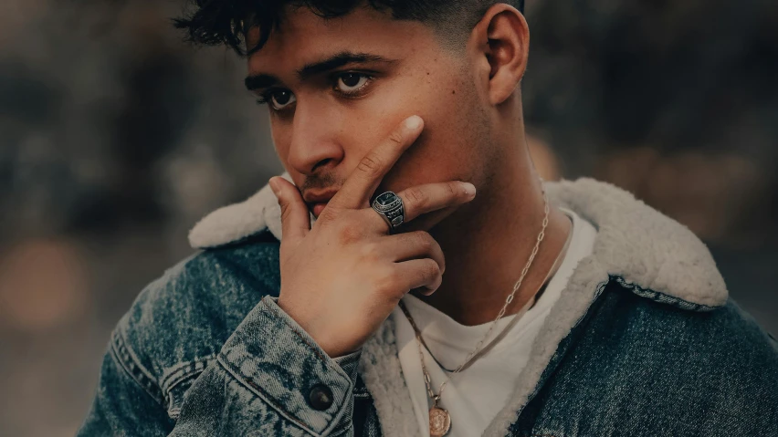 a man in a denim jacket smoking a cigarette, trending on pexels, realism, rapper jewelry, cute boy, middle eastern skin, wearing jewelry