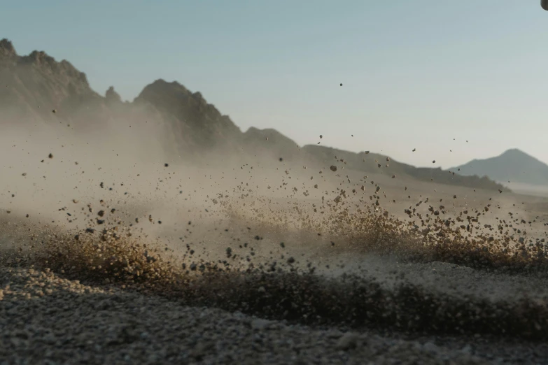 a person riding a dirt bike on a dirt road, an album cover, unsplash, visual art, sand particles, swarming with insects, black volcano afar, cinematic mid shot fight