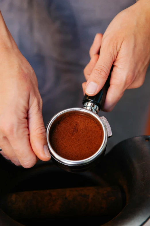 a close up of a person pouring a cup of coffee, “ iron bark, detailed product image, looking towards camera, grind