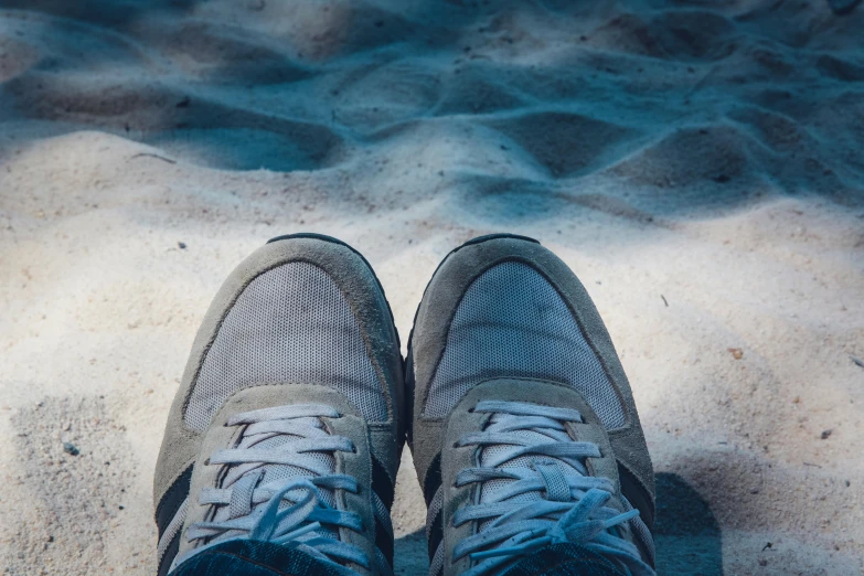 a pair of shoes sitting on top of a sandy beach, profile image, blue and grey, sneakers, soft shade