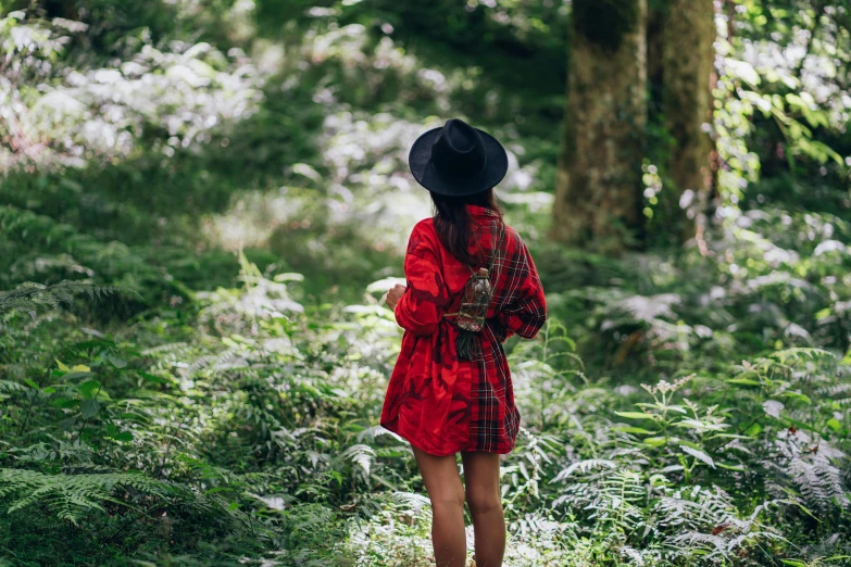 a woman in a red dress and black hat walking through a forest, a photo, flannel, traveller, foliage clothing, short