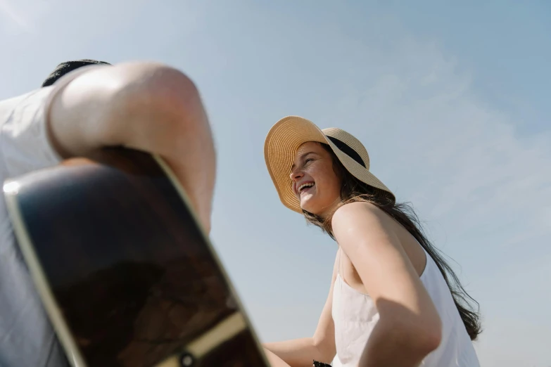 a woman standing next to a man holding a guitar, pexels contest winner, happening, wearing wide sunhat, avatar image, low angle photo, smiling laughing