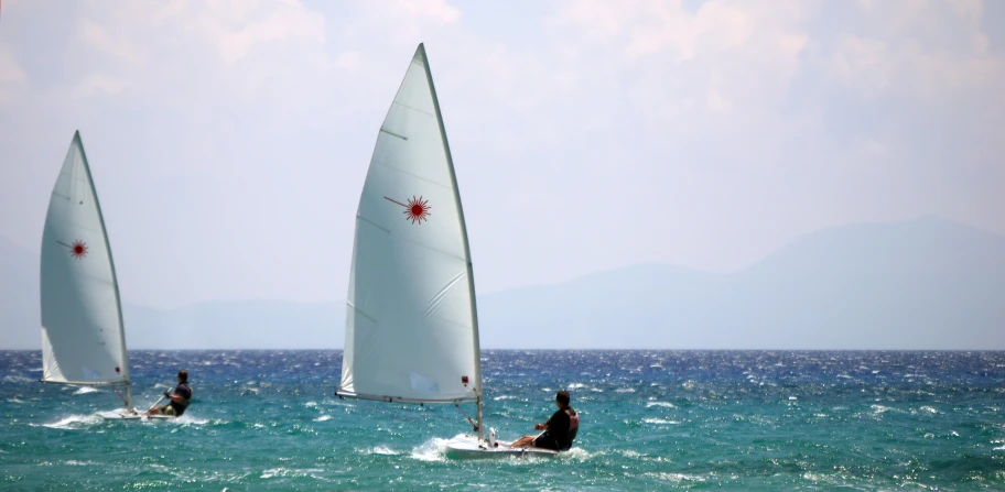 a group of people riding sailboats on top of a body of water, in the sun, profile image, greek nose, laser beam ; outdoor