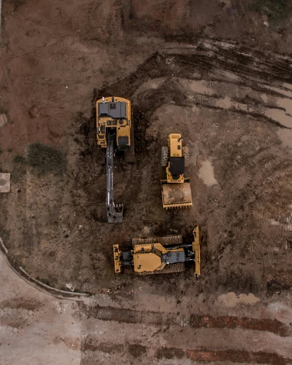 a group of construction equipment sitting on top of a dirt field, by Adam Marczyński, ariel view, profile image, cinematic image, slightly pixelated