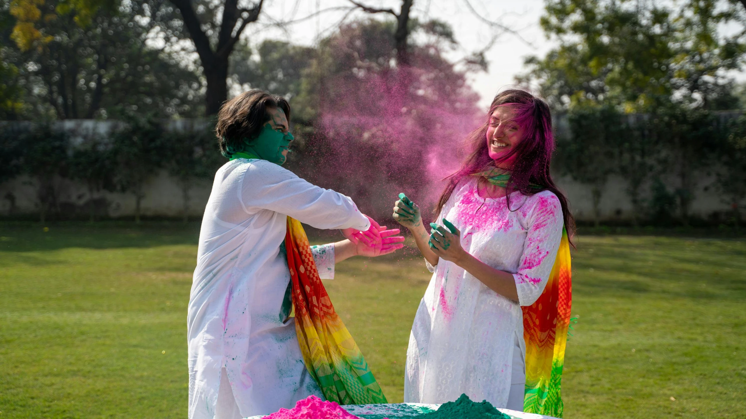 a couple of people that are standing in the grass, a colorized photo, pexels contest winner, color field, festive colors, hindu aesthetic, playing, covered in white flour