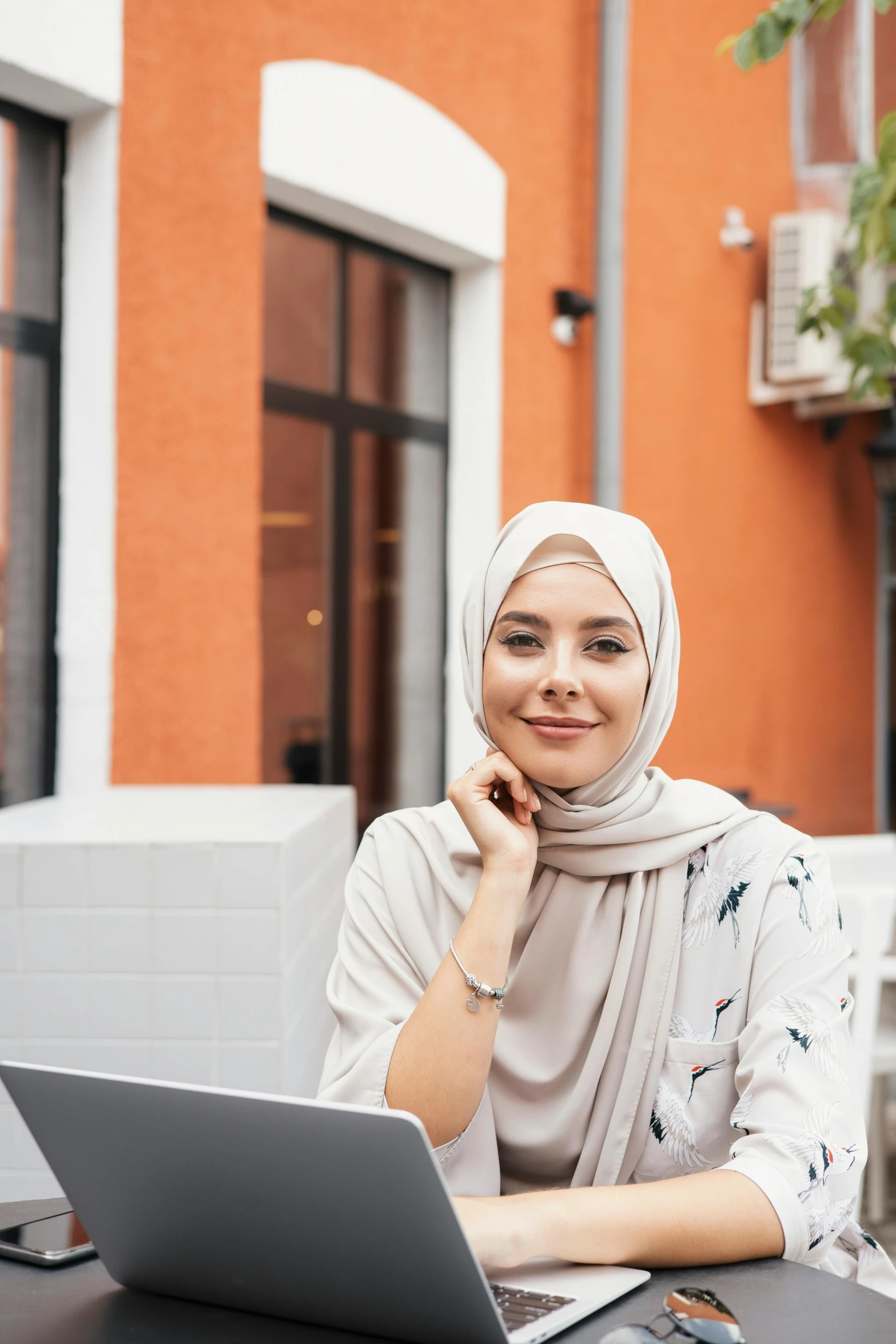 a woman sitting at a table with a laptop, inspired by Maryam Hashemi, trending on pexels, hurufiyya, front portrait, malaysian, caucasian, high quality picture