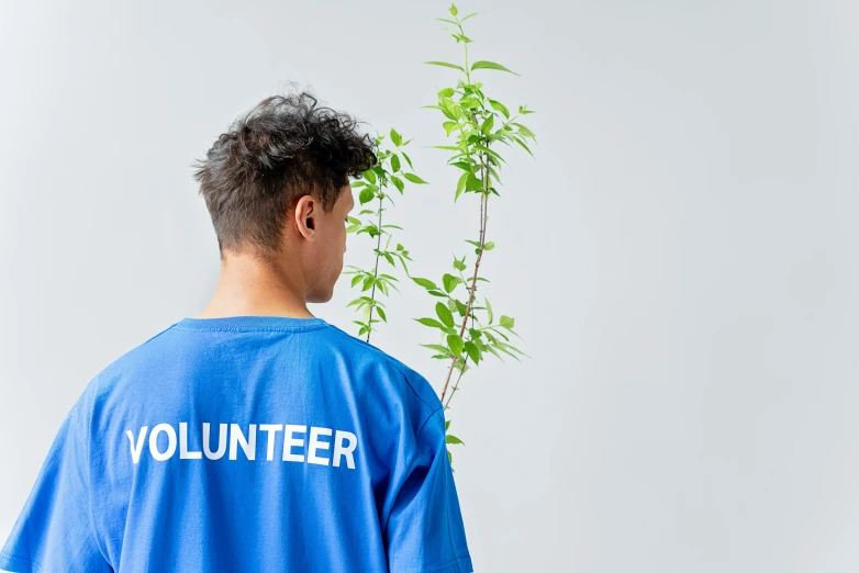 a man standing in front of a plant wearing a volunteer t - shirt, by Julia Pishtar, pexels contest winner, blue clothing, set against a white background, 15081959 21121991 01012000 4k, thumbnail