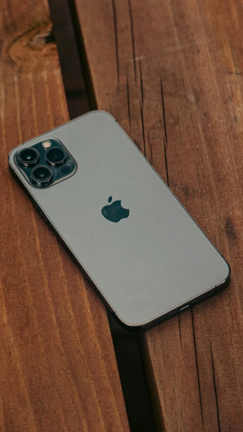 an iphone sitting on top of a wooden table, by Robbie Trevino, pexels, 2 5 6 x 2 5 6, sony nicon iphone 1 3 pro max, grey skin, covered