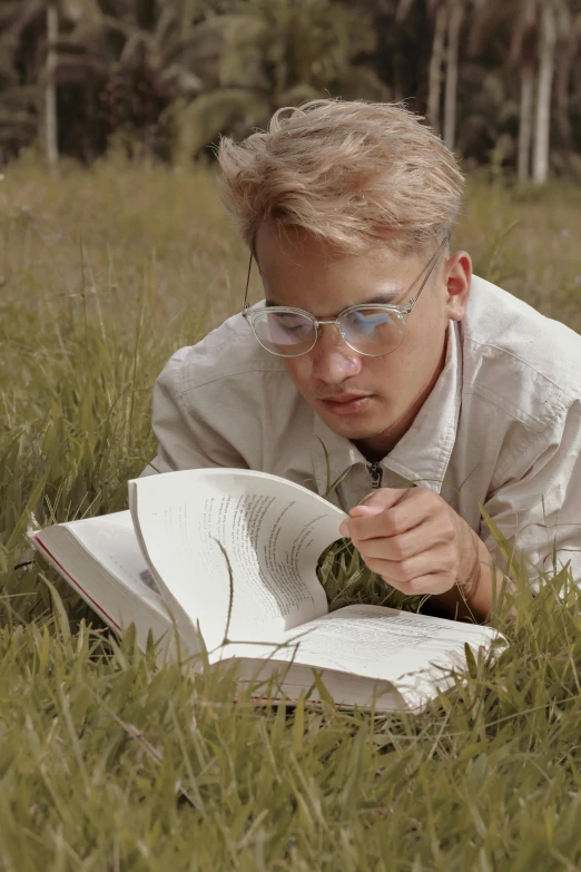 a man laying in the grass reading a book, inspired by Oskar Lüthy, wearing small round glasses, still from a nature documentary, blonde guy, ignant