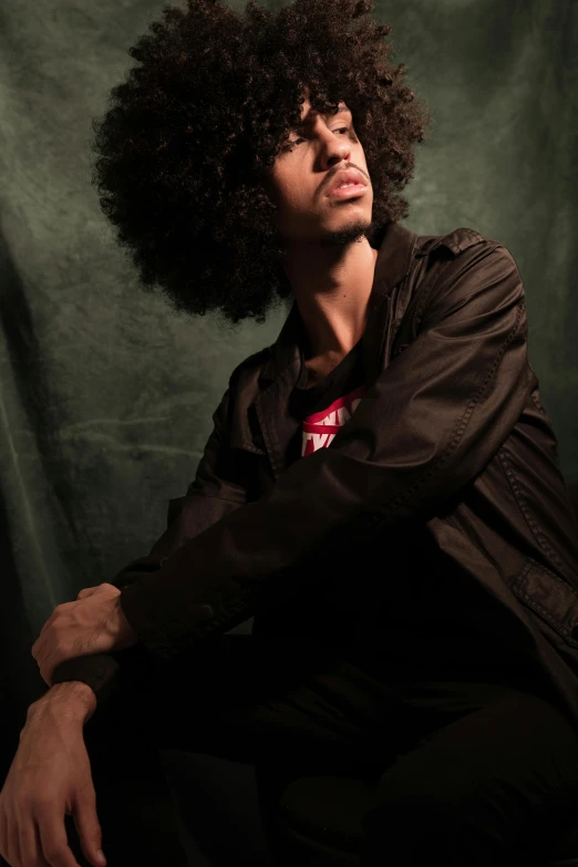 a man with an afro sitting on a chair, inspired by Afewerk Tekle, pexels contest winner, portrait of a rugged young man, middle eastern, promotional image, smooth background