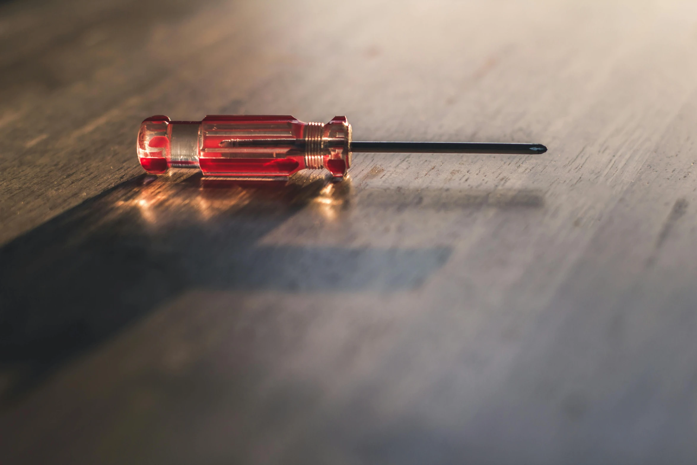 a small screwdriver sitting on top of a wooden table, by Jason Felix, pexels, detailed glowing red implants, ground level shot, instagram post, indoor shot