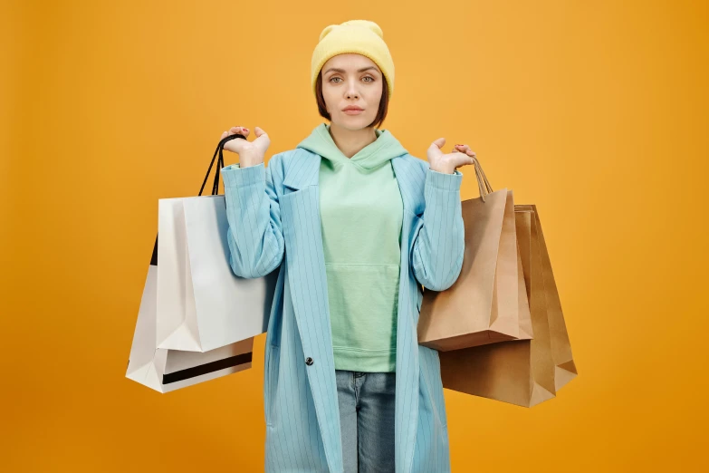 a woman in a blue coat holding shopping bags, trending on pexels, wearing a yellow hoodie, awkward situation, sea - green and white clothes, 🦩🪐🐞👩🏻🦳