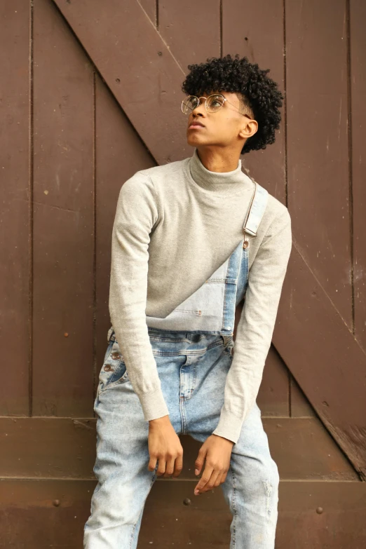 a man in overalls leaning against a wooden door, an album cover, by Everett Warner, trending on pexels, renaissance, sleeveless turtleneck, black teenage boy, dressed in a gray, profile pic