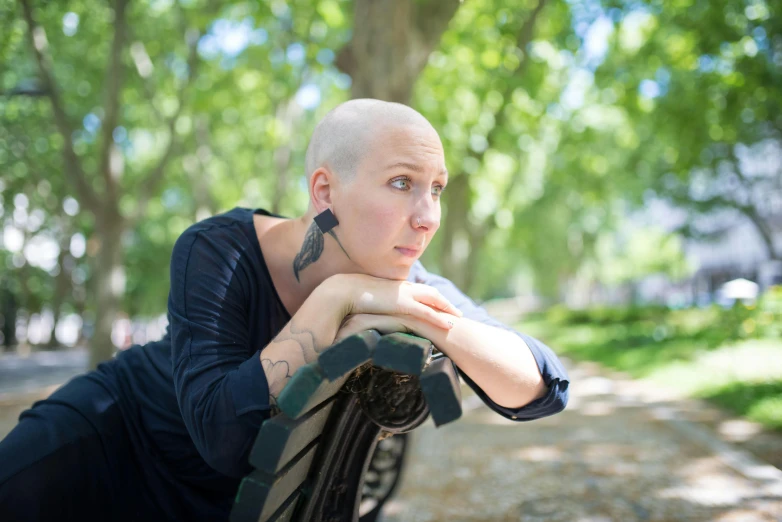 a woman sitting on a bench in a park, a portrait, pexels contest winner, renaissance, shaved bald head, lachlan bailey, avatar image, the cure for cancer