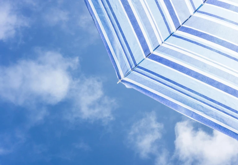 a blue and white striped umbrella against a blue sky, unsplash, sarong, rectangle, looking up onto the sky, in a sun lounger