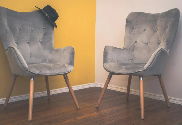 a couple of chairs sitting on top of a hard wood floor, pexels contest winner, modernism, tall hat, silver and yellow color scheme, standoff, armchair