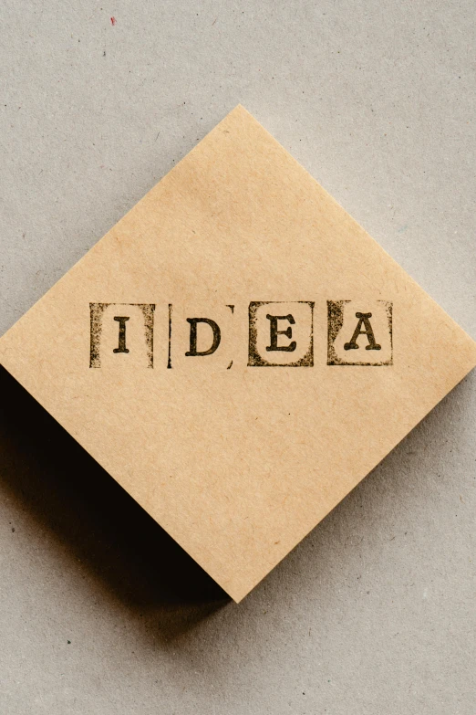 a piece of cardboard sitting on top of a table, trending on pexels, neo-dada, rubber stamp, innovation, concrete poetry, edison bulb