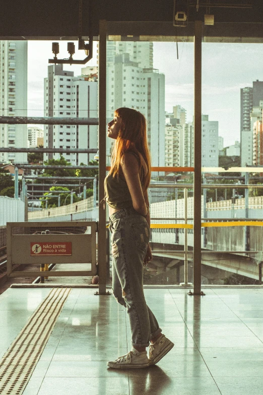 a woman standing in a train station looking out the window, inspired by Elsa Bleda, happening, sao paulo in the year 2 0 7 0, standing in a parking lot, skybridges, photo of young woman