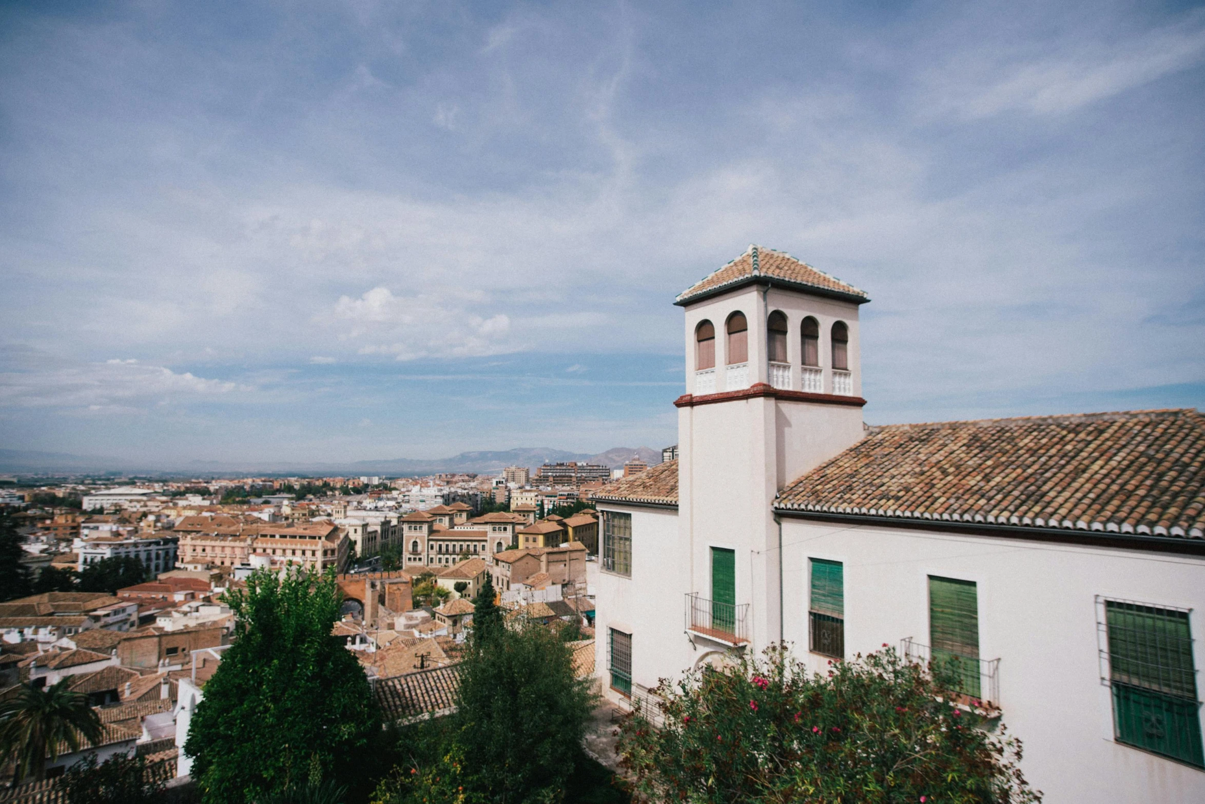 a white building with a clock tower on top of it, inspired by Serafino De Tivoli, unsplash, panoramic view, spanish, square, an olive skinned